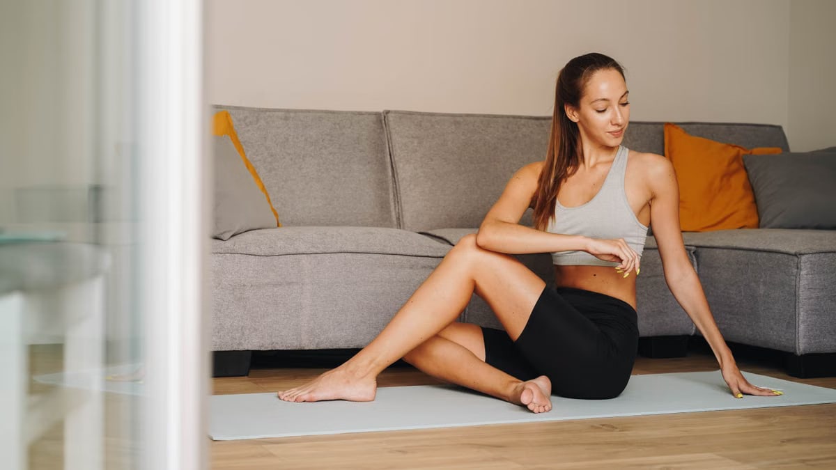 Woman practicing yoga indoors on a mat, embodying fitness and tranquility.